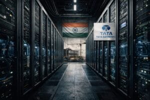 A data center hallway with server racks, an Indian flag on the back wall, a Tata Electronics sign, and a construction site visible through an opening.