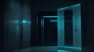 A dimly lit room with a glass door partially open, revealing blue light from an adjacent space.
